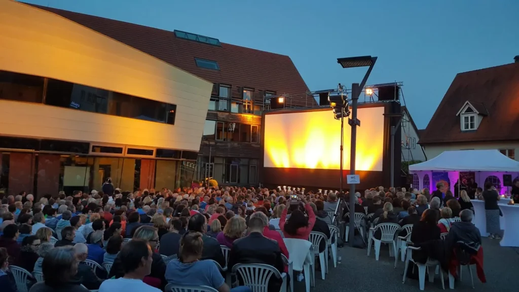 Foto von Marktplatz in Abendstimmung mit Menschen und Leinwand beim Open-Air-Kino Event in Weilheim