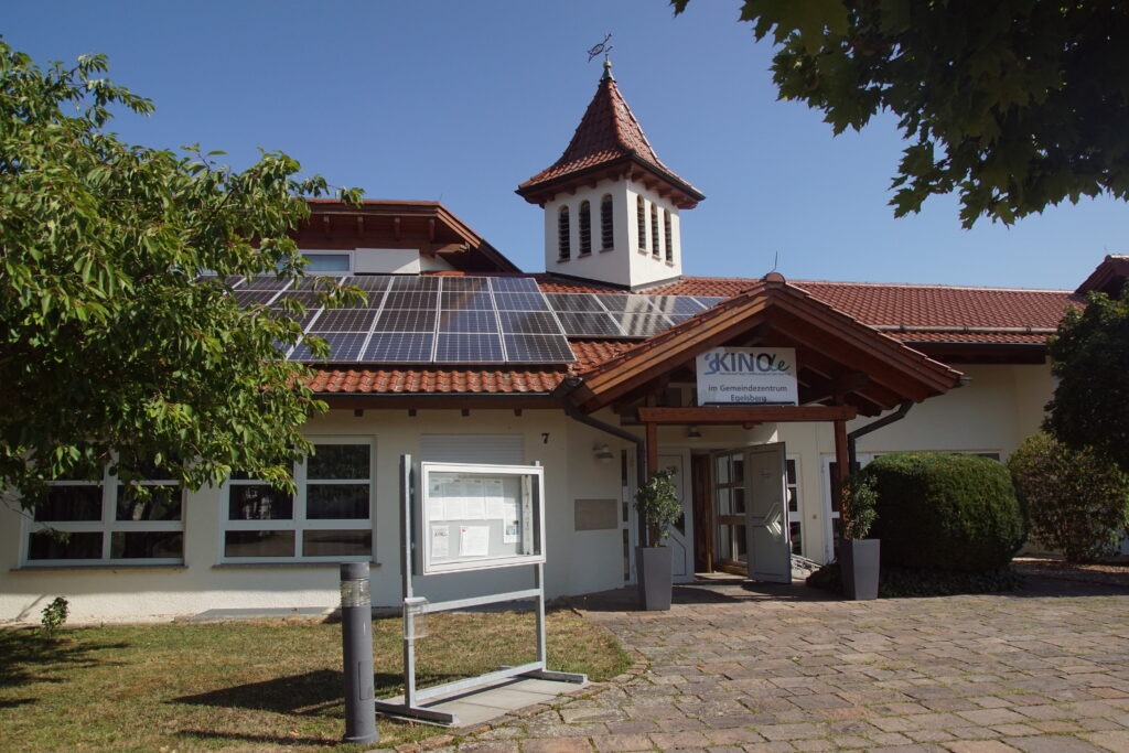 Kinole Gemeindezentrum Egelsberg Weilheim an der Teck Außenansicht, Gebäude mit rotem Ziegeldach, Solarpanelen, kleinem Türmchen, überdachter Eingangsbereich