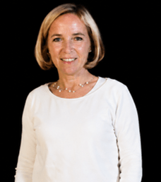 Portrait von Sabine Reich, weißes T-Shirt, schwarzer Hintergrund, blonde schulterlange Haare